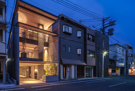 暖色のライトアップが美しい建物の夜景。暗闇に浮かび上がるコンクリートと木材の質感、そして洗練された和モダンのシルエット